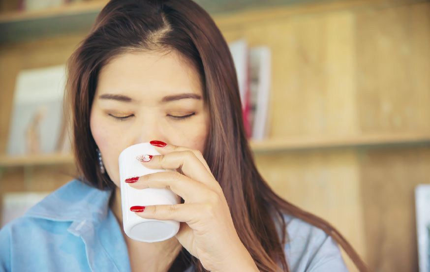 Woman drinking Turkish coffee from Aroom coffee vending machine. Coffee Vending Machine Manufacturer.